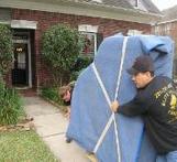 Movers bring a padded and protected grand piano into a residential home after being transported across several states.
